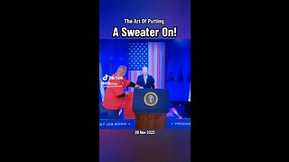 Joe Biden struggles to put on a sweater on stage