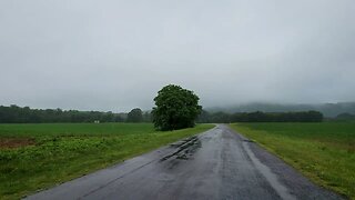 Rainfall on a lonely paved rural road through a grassy landscape in North America