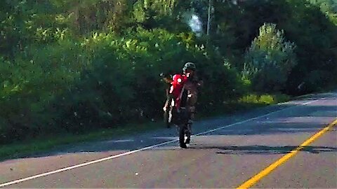Motorcyclist casually rides down highway on back wheel