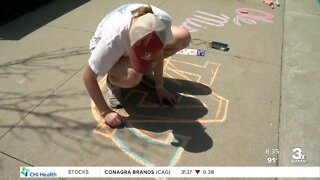 Omaha teen greets college baseball fans with hand-drawn team logos in the parking lot