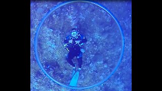 Dive master entertains clients with skillful with underwater bubble rings