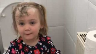 Une fillette surprise se lavant les cheveux au papier toilette