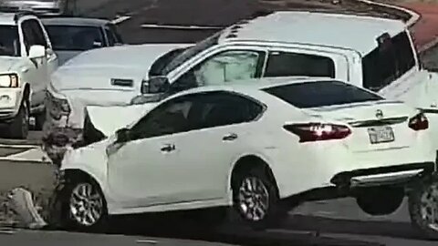 Driver of the white Nissan runs a red light at the intersection.