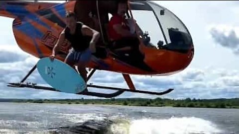 Jovem salta de helicóptero para prancha de surf