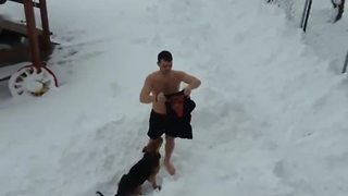 Crazy dude works out shirtless in the snow, dog happily joins him