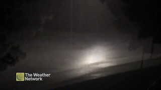Street lamp illuminates heavy rain on suburban road