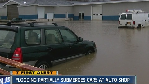 Flooded creek spills into auto shop parking lot