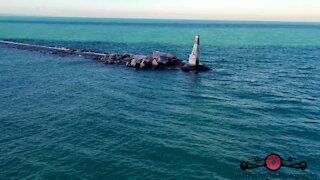 Relaxing drone footage of frozen lakeshore & lighthouse waves