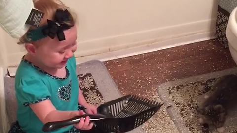 A Tot Girl Plays In A Bathroom With Her Cat’s Litter Box