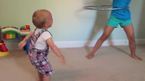 Tot Boy Falls With Laughter While His Sister Spins A Hula Hoop