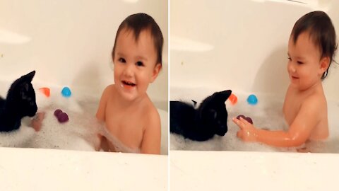 Adorable toddlers playing with cats while bathing are very friendly