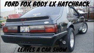 A Black Fox Body LX Hatchback Leaves a car show