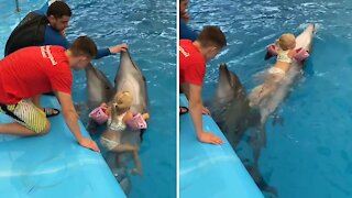 Fearless three-year-old girl rides on top of fast-swimming dolphin
