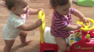 Baby preciously pushes twin sibling in toy car