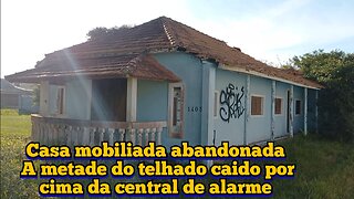 casa mobiliada abandonada com a metade do telhado desmoronado por cima da central de alarme na chuva