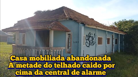 casa mobiliada abandonada com a metade do telhado desmoronado por cima da central de alarme na chuva