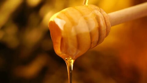 Footage organic honey dripping from wooden honey spoon background