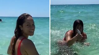Woman in the ocean catches fish with her bare hands