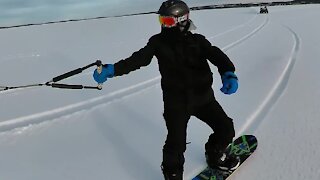 Snowboarder gets "towed" across frozen lake