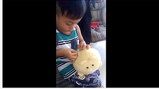 Skillful little boy sews together his damaged stuffed animal