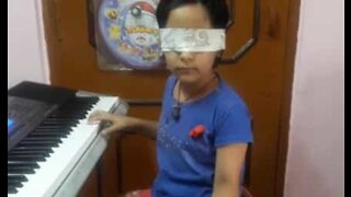 Menina dotada toca piano com olhos vendados