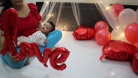 mom making 2 months old baby wear valentine's day outfit for baby photoshoot at Home