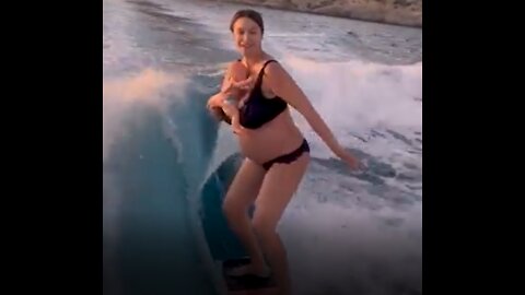 A pregnant mom surfing with a toy baby