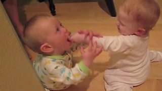 "Two Baby Boys in Footie Pajamas Fight Over Pacifier"