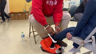Coca-Cola Consolidated employee helping a student try on their shoes