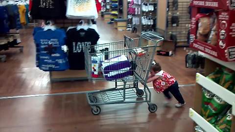 "Tot Girl Pushes Shopping Cart In Store"