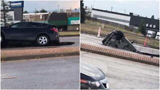 Un buco nell'asfalto inghiotte l'auto intrappolata