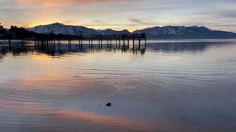 Rippling water and rainbow clouds; ducks, cruise ships, and visitors on docks: Sunset at Lake Tahoe.