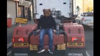 Man with bear mask hitches ride on back of truck