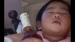 Bebê gosta de dormir com uma garrafa de licor nas mãos