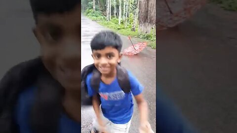 School boy is going crazy on a rainy day in the village street