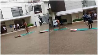 Residents paddle board through flooded streets in the Philippines