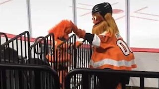 Une fan de hockey sur glace danse avec la mascotte