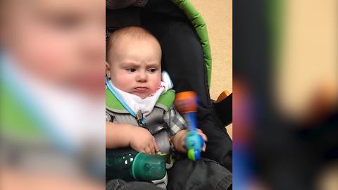 Grumpy Baby Boy Bangs A Rattle Against His Stroller