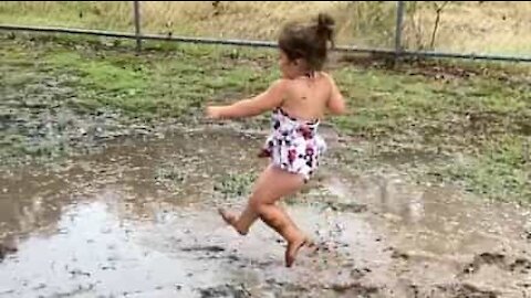 Little girl has great fun in muddy puddle
