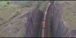 Guy slacklines over train track