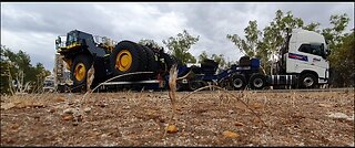 Volvo semi with lowboy low loader transporting oversize load Komatsu mining haul truck