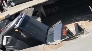 Caminhão de lixo cai dentro de shopping após estacionamento ceder