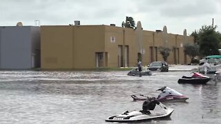 People ride jet skis through flooded Miami streets