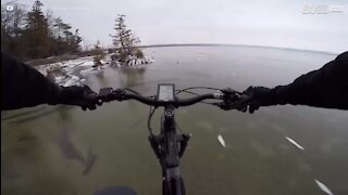 Ciclista atravessa lago gelado transparente