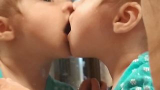 Sweet baby shares kisses with her reflection