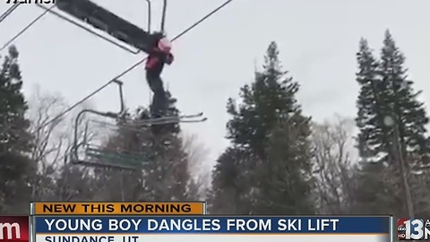 Young boy dangles from ski lift