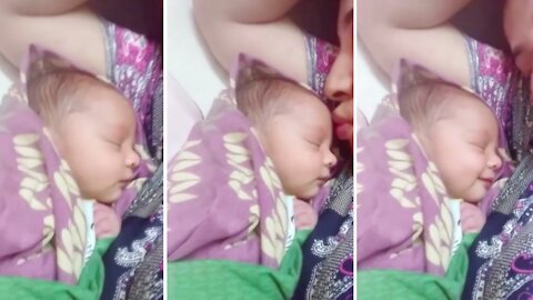 New born baby smiles when mommy kissed her