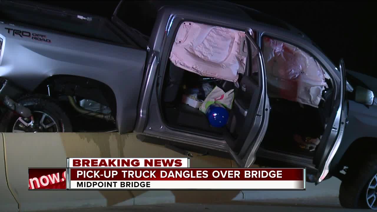 Pick-up truck dangles over bridge