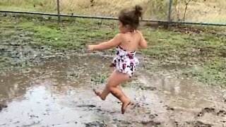 Cette petite fille s'amuse avec une flaque de boue