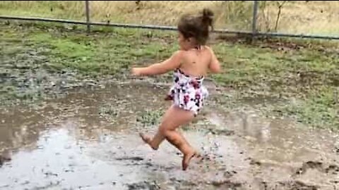 Cette petite fille s'amuse avec une flaque de boue